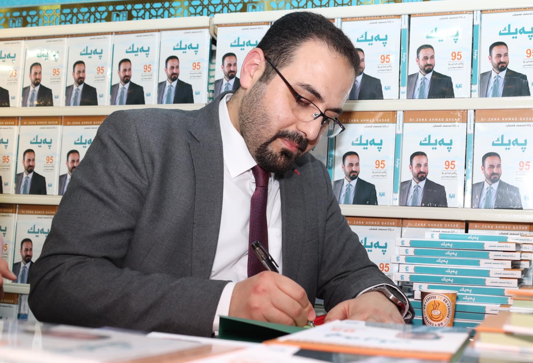 Dr. Zana Ahmad Qasab signing copies of his book Paik at the Erbil International Fair